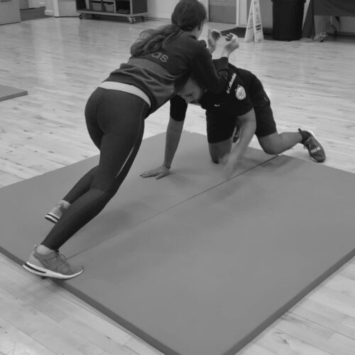 woman and man on a mat practicing martial arts